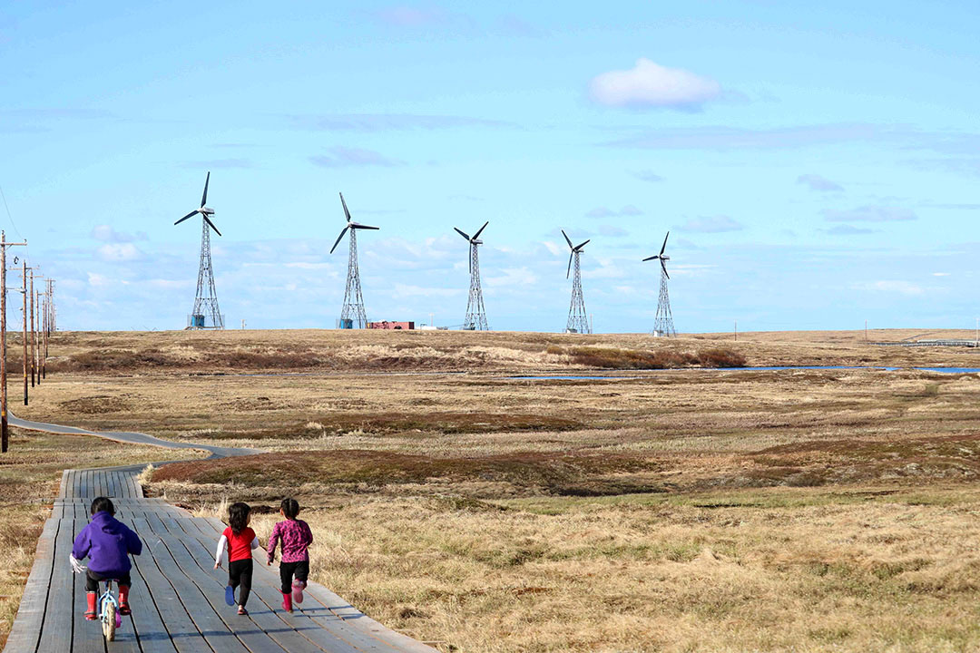 Children run along the boardwalk in the remote northern community of Kongiganak on Alaska’s Yukon Kuskokwim Delta where wind energy combined with a battery storage system provides up to 100 per cent of the community’s electric needs. (Photo: Amanda Byrd)